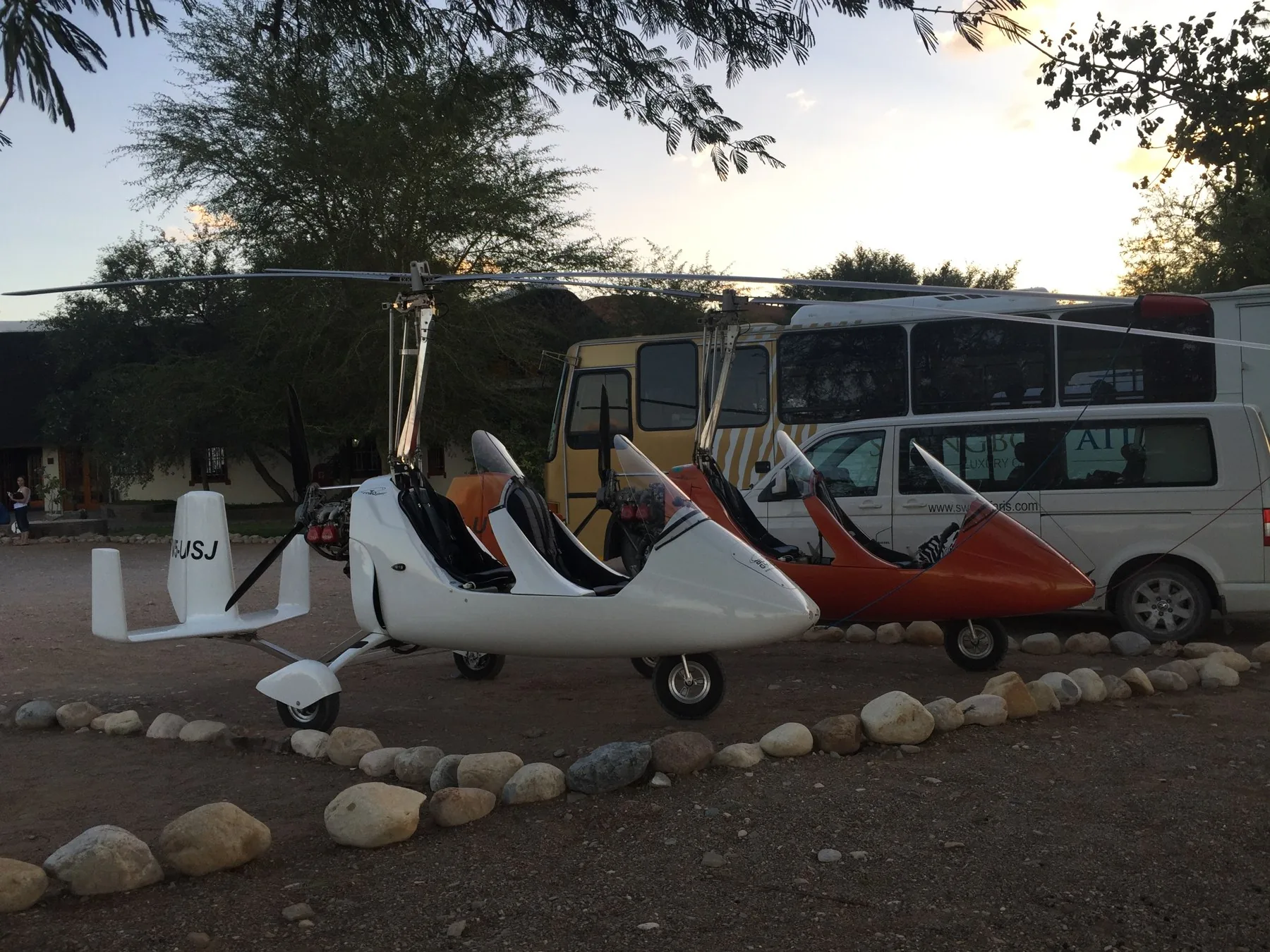 Gyros neben einem Bus und Fahrzeugen im Schatten an einer Lodge in Namibia