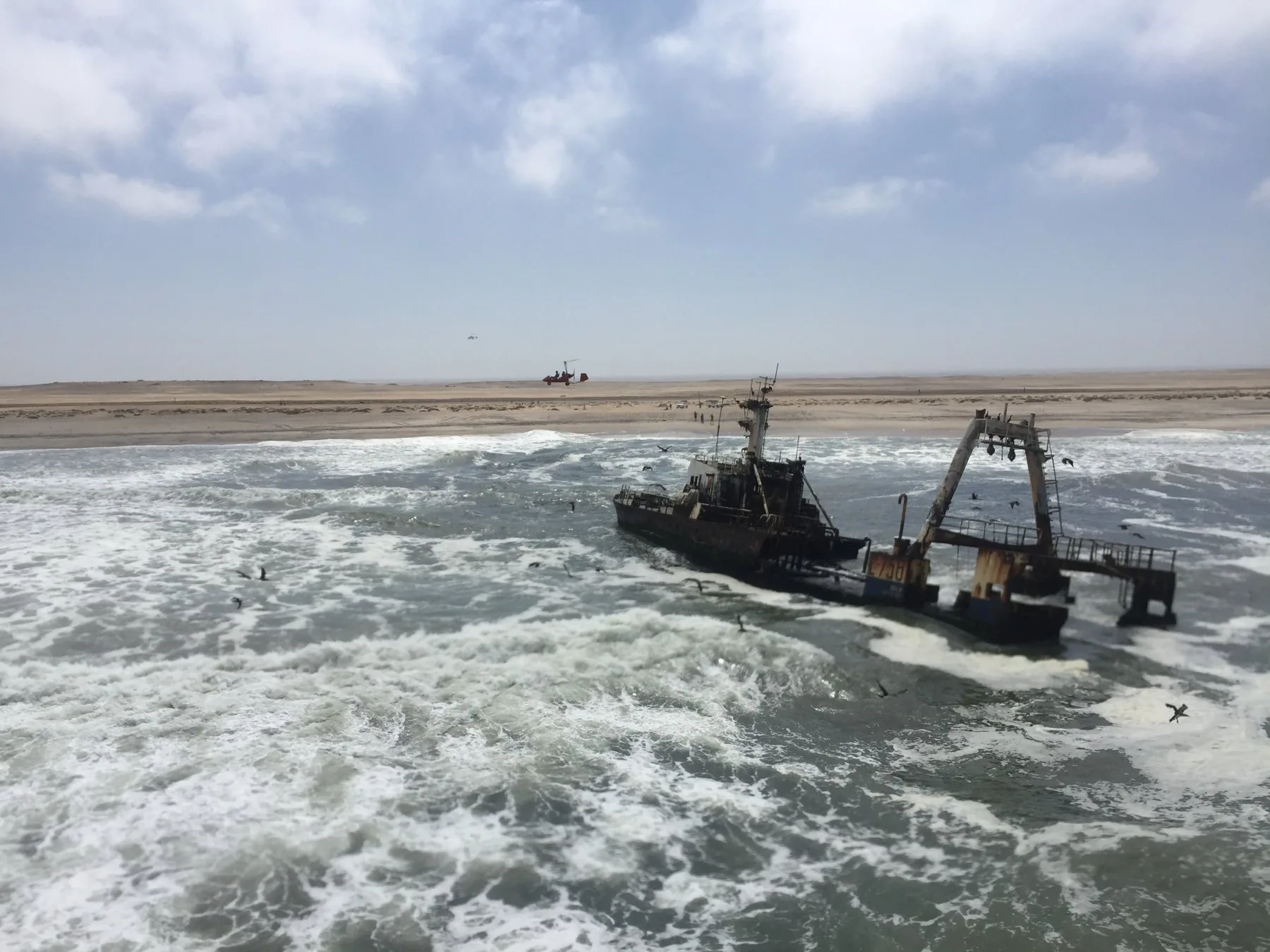 Schiffswrack in der Atlantikbrandung mit einem Gyro über Namibias Küste